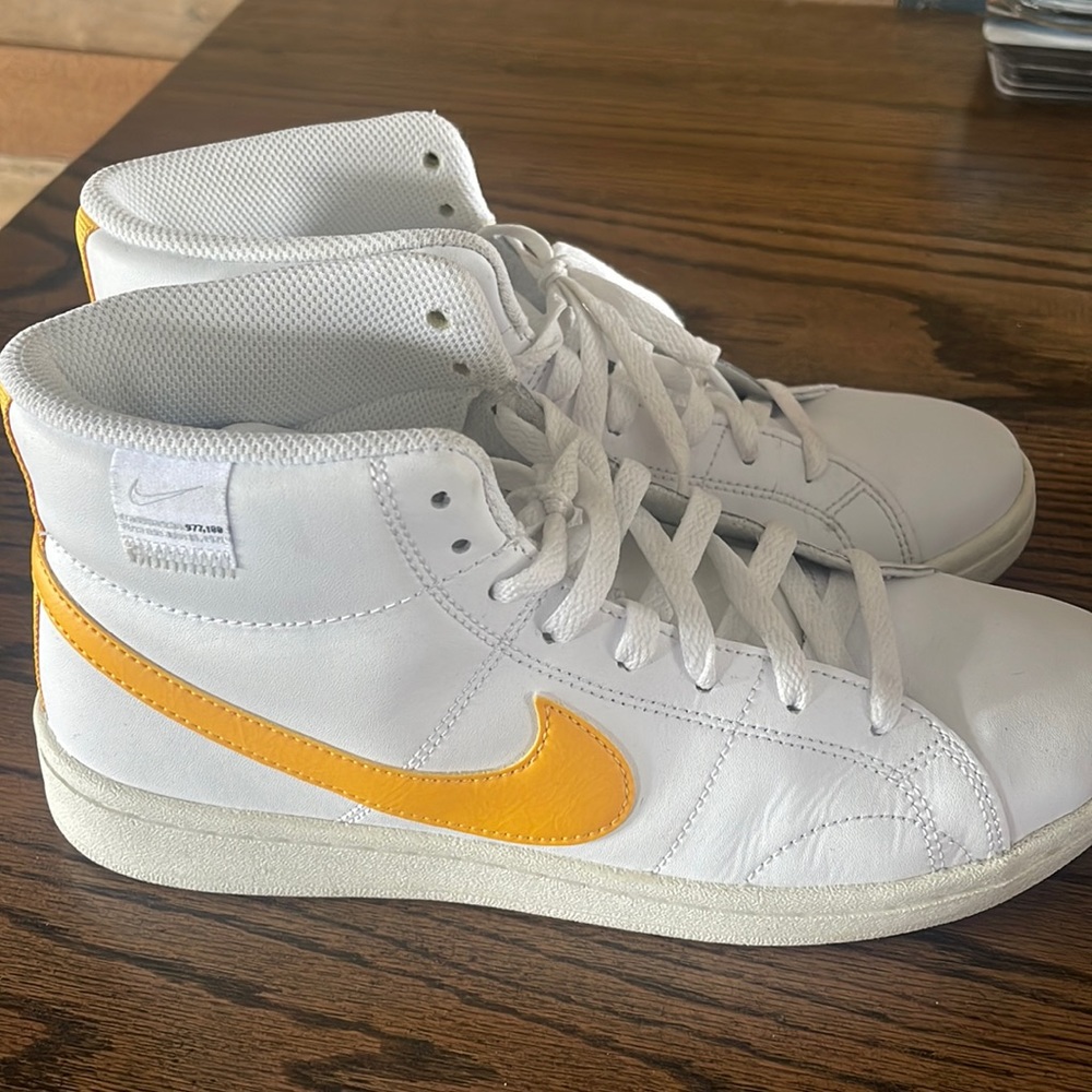 White Nikes with yellow swoosh.